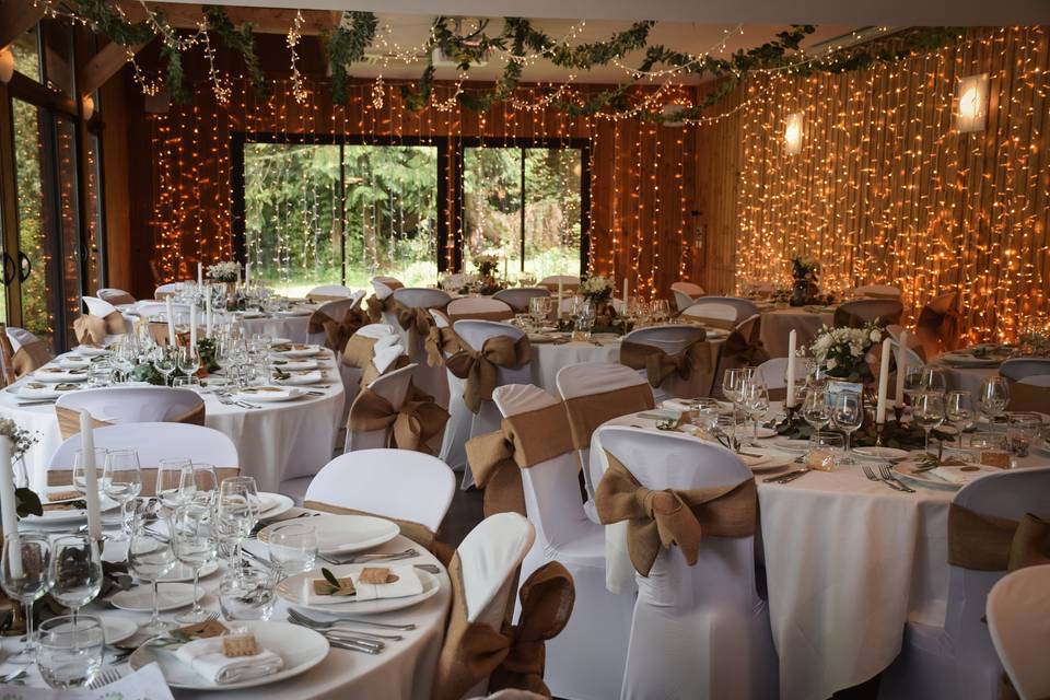 Décoration mariage champêtre avec nœuds de chaise en toile de jute et guirlandes lumineuses réalisée par Esprit Fête wedding planner Rennes