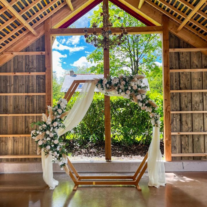 Arche de cérémonie laïque au Haras du Reuzel avec décoration florale et structure en bois en Ille-et-Vilaine